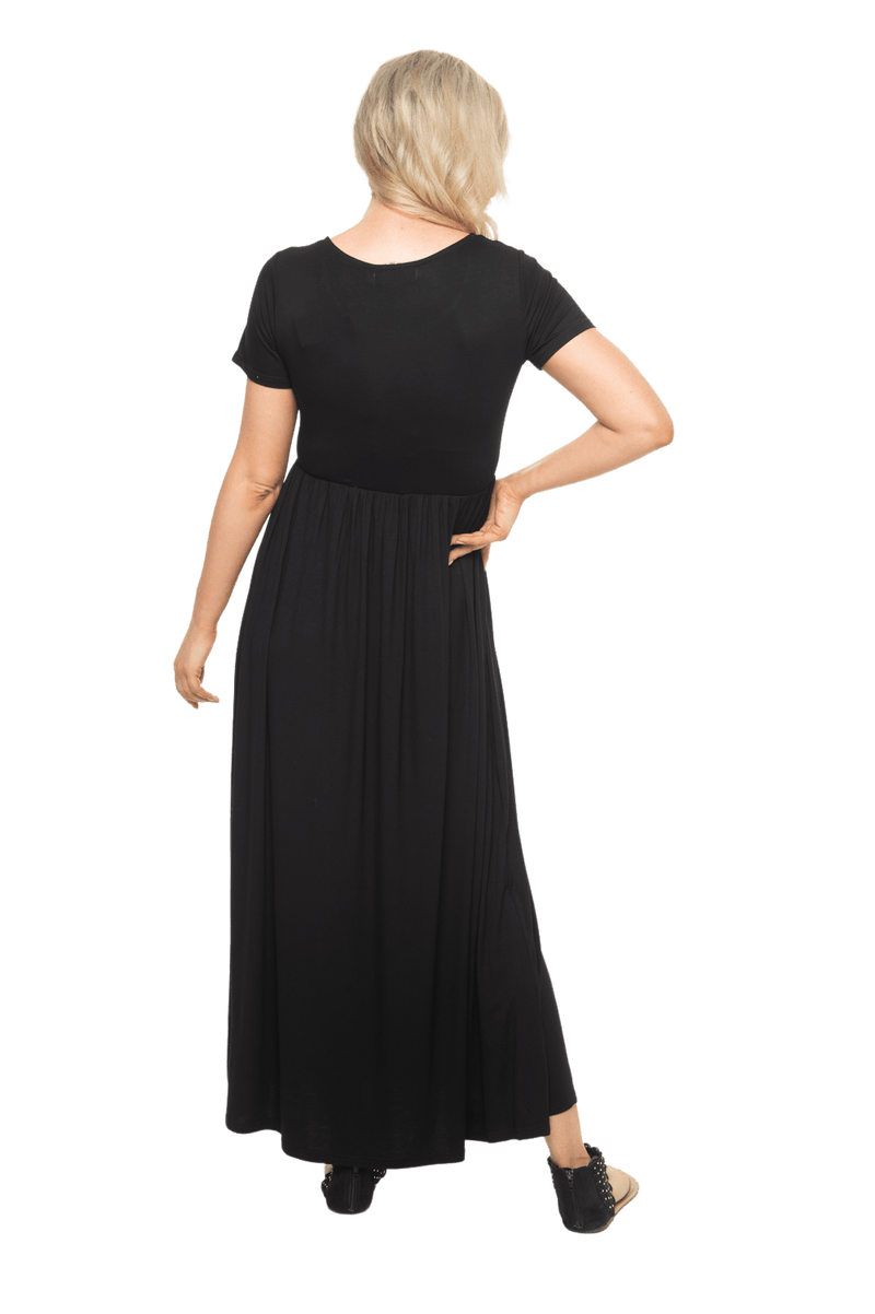 Petite model facing the back wearing black maxi dress, featuring  rounded neckline, and a gently fitted bodice, gathering above the waist. Riley available in sizes 6-26