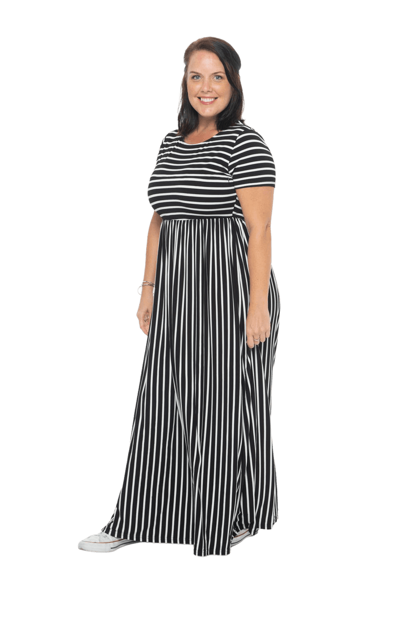 Brunette model facing the side wearing black and white striped maxi dress, featuring rounded neckline, and a gently fitted bodice, gathering above the waist. Riley available in sizes 6-18