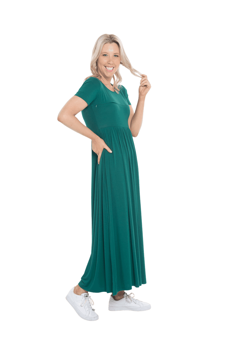 Petite model facing the side wearing bottle green maxi dress, featuring  rounded neckline, and a gently fitted bodice, gathering above the waist. Riley available in sizes 6-26