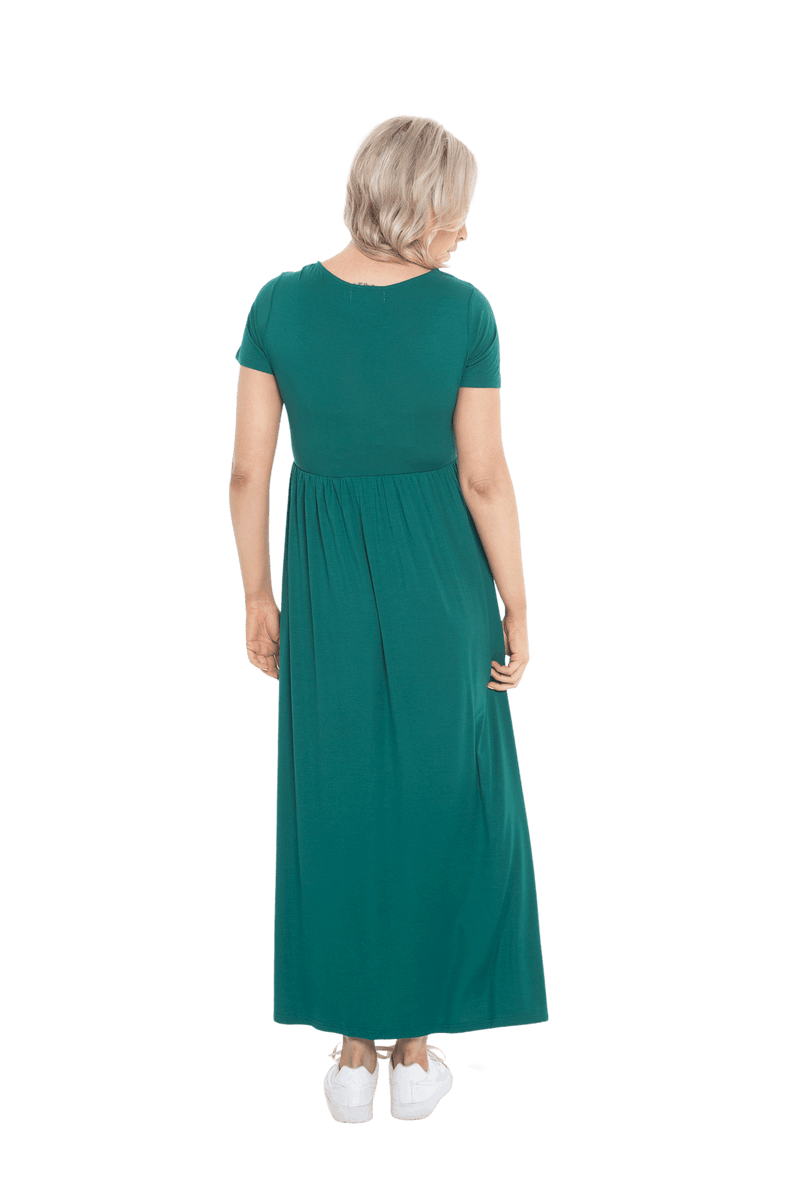 Petite model facing the back wearing bottle green maxi dress, featuring  rounded neckline, and a gently fitted bodice, gathering above the waist. Riley available in sizes 6-26
