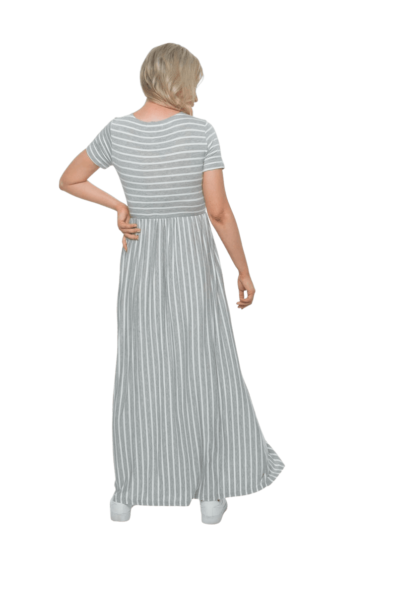 Petite model facing the back wearing light grey and white striped maxi dress, featuring rounded neckline, and a gently fitted bodice, gathering above the waist. Riley available in sizes 6-18