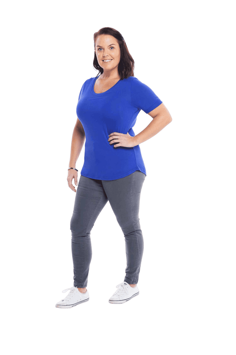 Petite model facing the side wearing cobalt blue short sleeved tee, featuring rounded neckline, and scooped hem. Stevie available in sizes 6-18