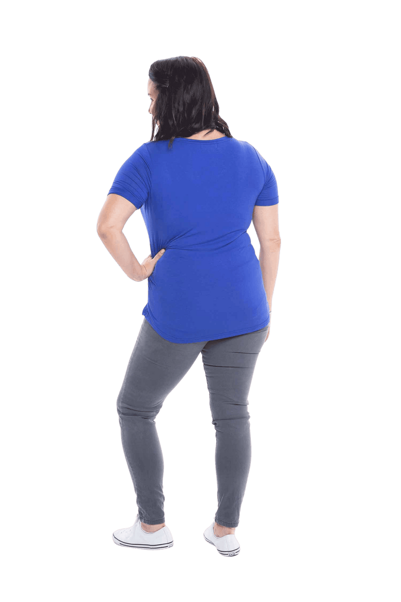 Petite model facing the back wearing cobalt blue short sleeved tee, featuring rounded neckline, and scooped hem. Stevie available in sizes 6-18