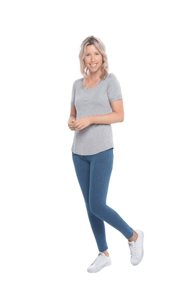 Petite model facing the side wearing light grey short sleeved tee, featuring rounded neckline, and scooped hem. Stevie available in sizes 6-26