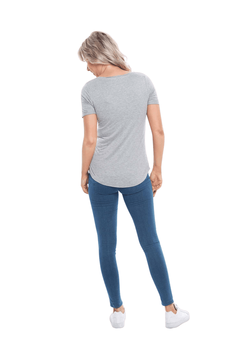 Petite model facing the back wearing light grey short sleeved tee, featuring rounded neckline, and scooped hem. Stevie available in sizes 6-26