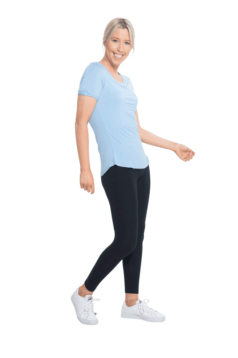 Petite model facing the side wearing light blue short sleeved tee, featuring rounded neckline, and scooped hem. Stevie available in sizes 6-18