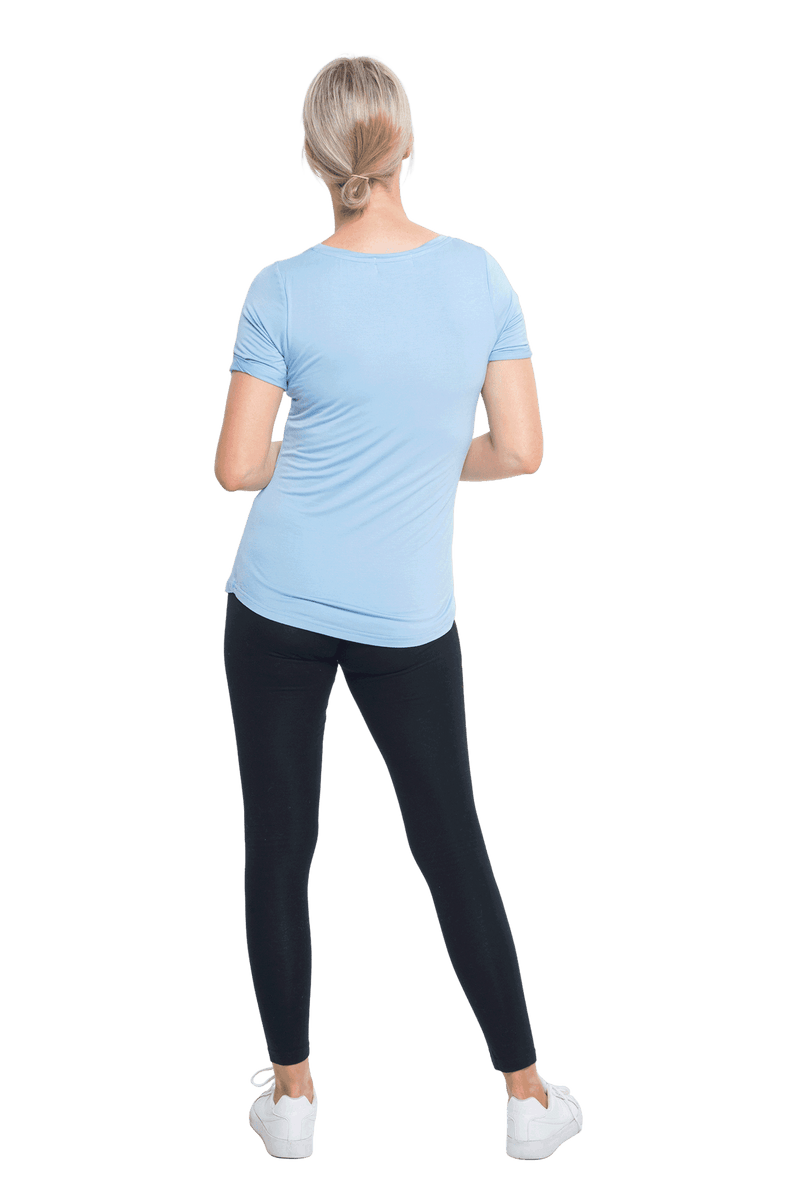 Petite model facing the back wearing light blue short sleeved tee, featuring rounded neckline, and scooped hem. Stevie available in sizes 6-18