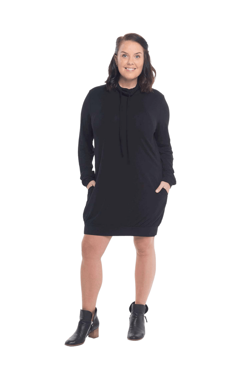 Brunette model facing the camera wearing black long sleeved tunic as a dress with boots, featuring pockets and a faux hoodie collar in a comfy, relaxed fit. Tori available in sizes 6-18