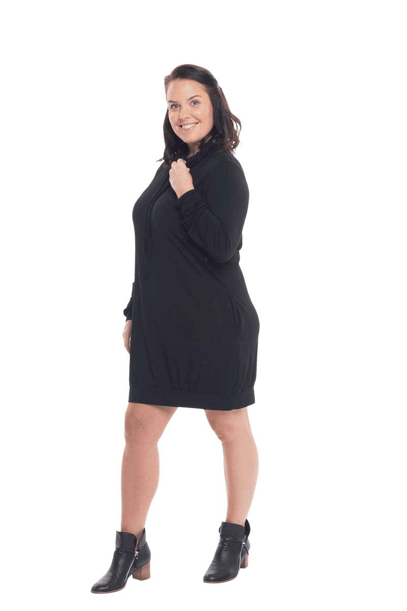 Brunette model facing the side wearing black long sleeved tunic, featuring pockets and a faux hoodie collar in a comfy, relaxed fit. Tori available in sizes 6-18