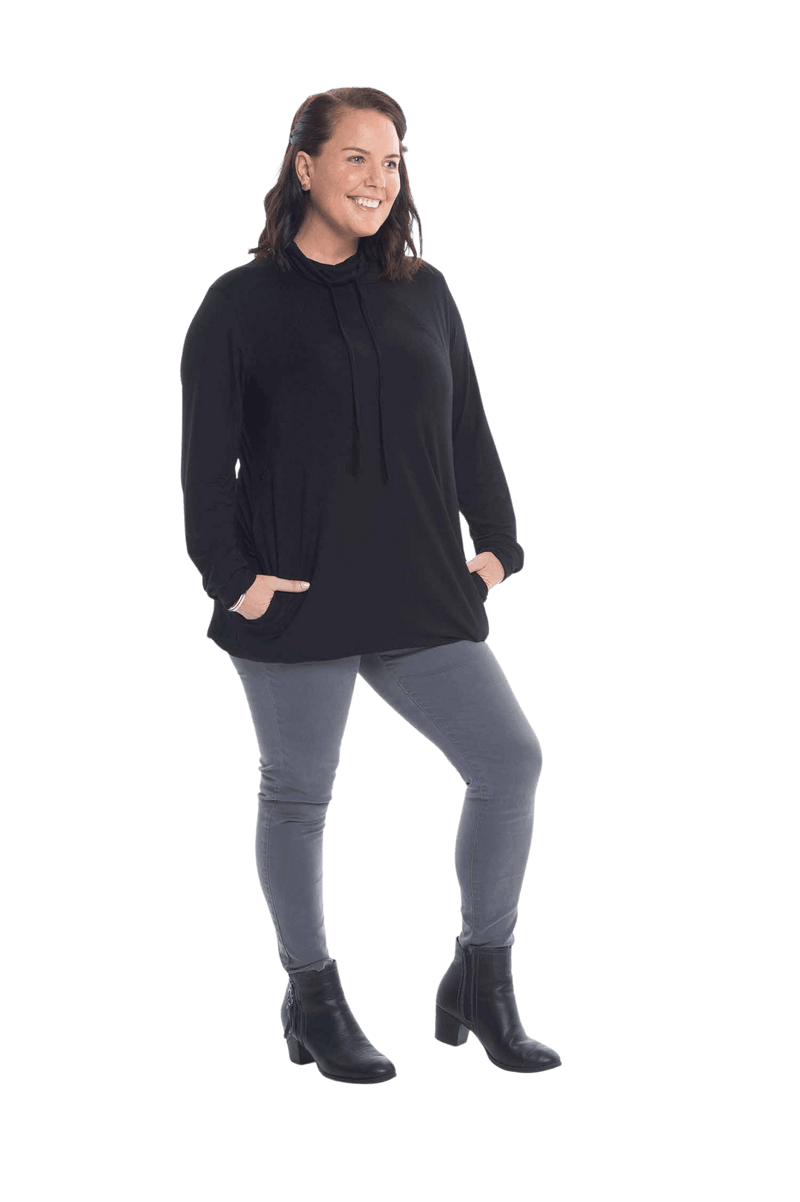 Brunette model facing the camera wearing black long sleeved tunic as a top with jeans, featuring pockets and a faux hoodie collar in a comfy, relaxed fit. Tori available in sizes 6-18