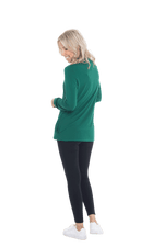 Petite model facing the back wearing bottle green long sleeved tunic as a top with black pants, featuring pockets and a faux hoodie collar in a comfy, relaxed fit. Tori available in sizes 6-26
