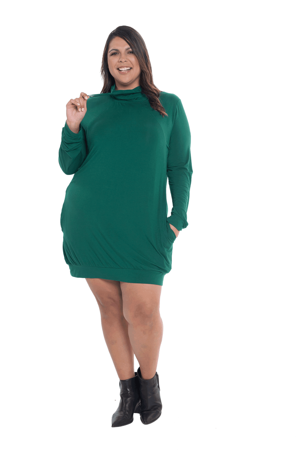 Curvy model facing the camera wearing bottle green long sleeved tunic as a dress with boots, featuring pockets and a faux hoodie collar in a comfy, relaxed fit. Tori available in sizes 6-26