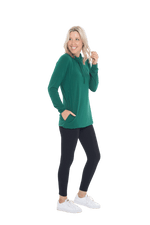 Petite model facing the side wearing bottle green long sleeved tunic as a top with black pants, featuring pockets and a faux hoodie collar in a comfy, relaxed fit. Tori available in sizes 6-26