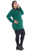 Curvy model facing the side wearing bottle green long sleeved tunic as a top with black pants, featuring pockets and a faux hoodie collar in a comfy, relaxed fit. Tori available in sizes 6-26